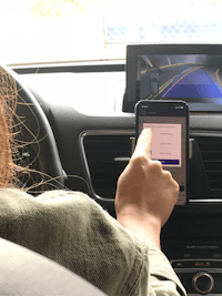 a woman in a car using a cell phone in the driver's seat